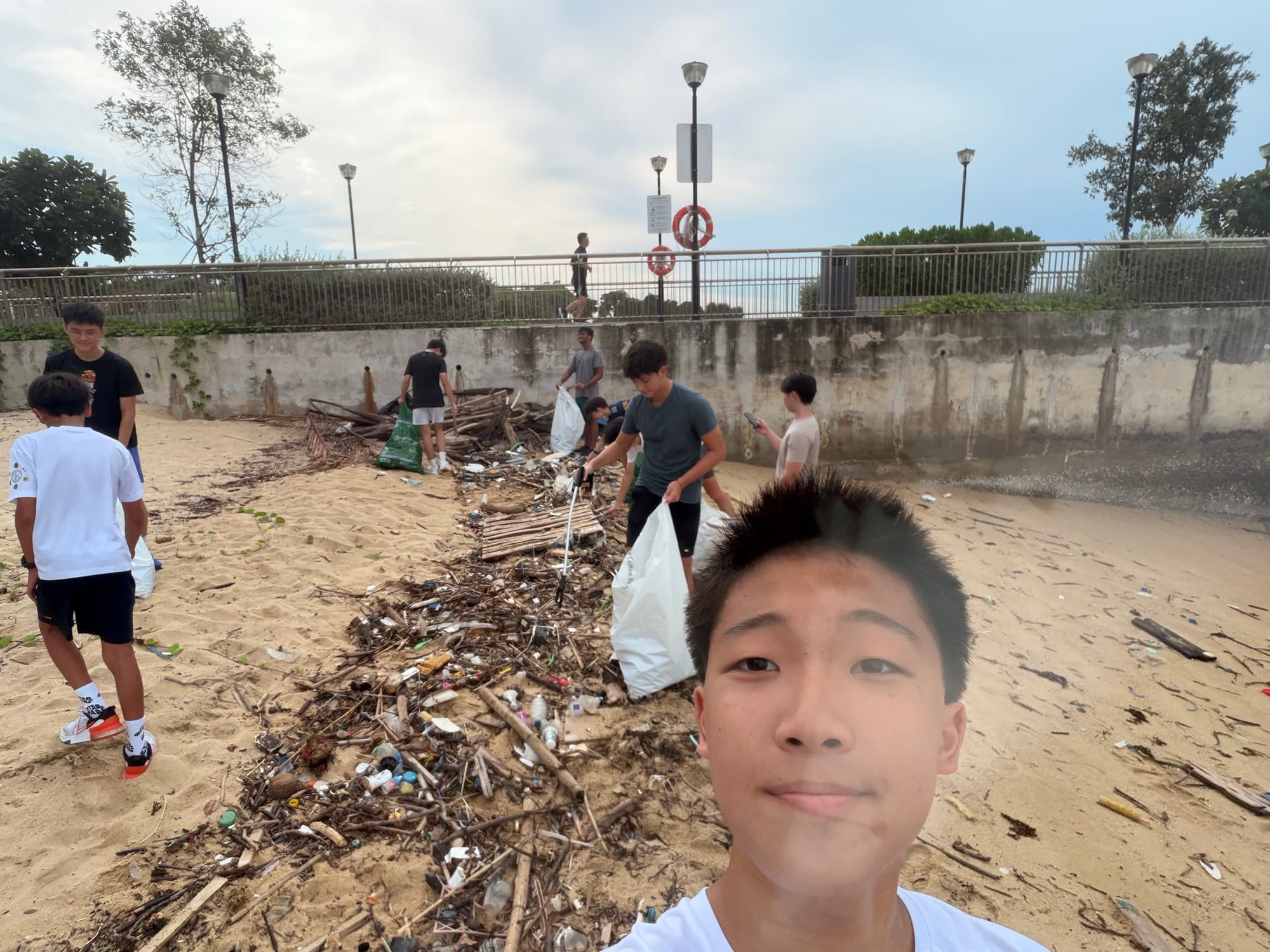 Sam at a beach cleanup with collected debris