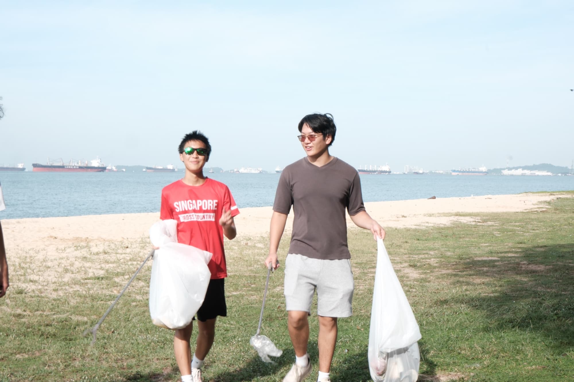 EcoMiles ploggers carrying collected waste bags on the beach